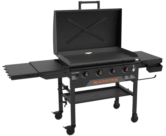 A Blackstone outdoor gas griddle with four burners, side shelves, a lower storage shelf, wheels for mobility, and a lid, shown on a white background.